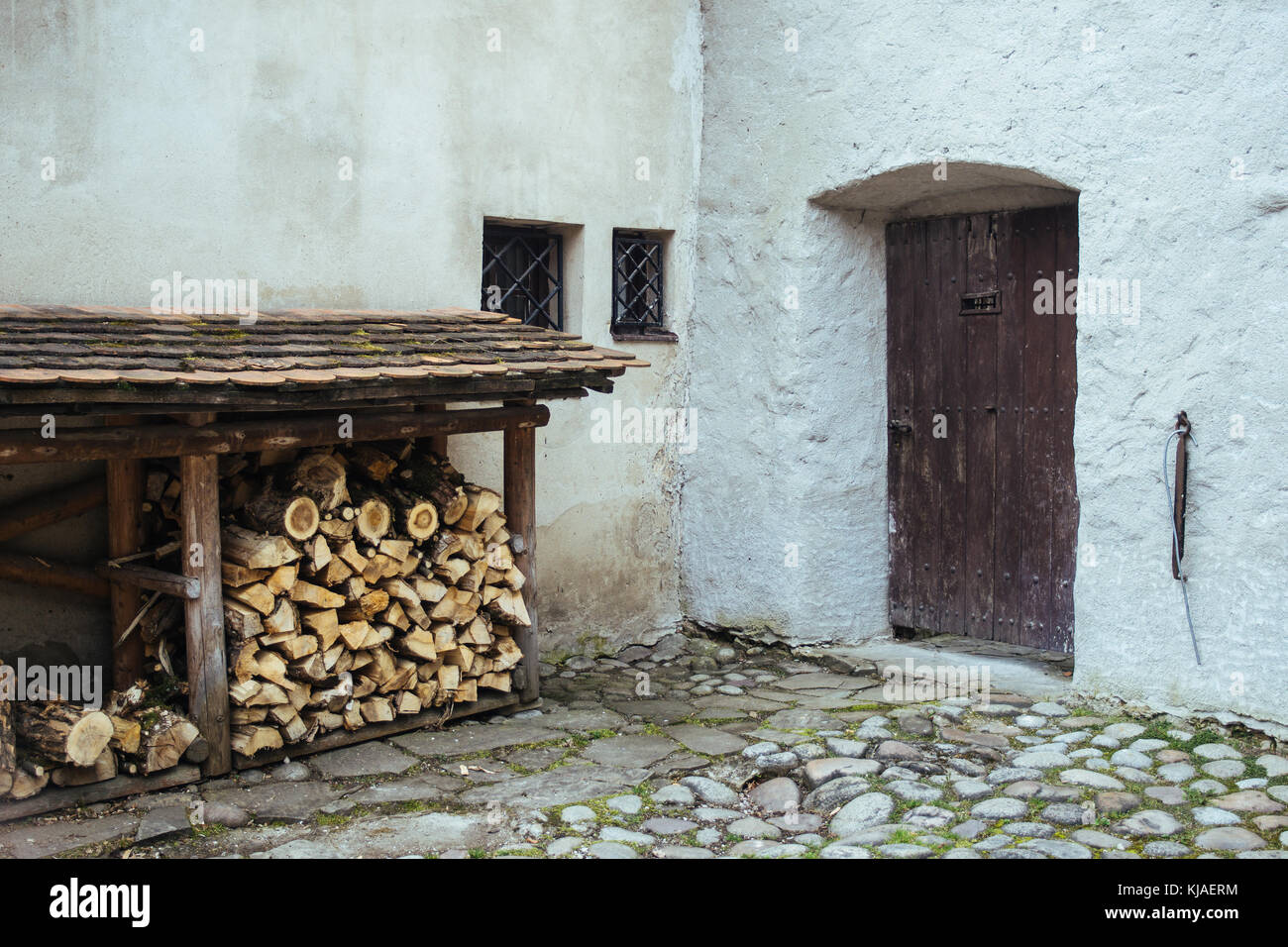 Pile of firewood against an old stone building corner Stock Photo