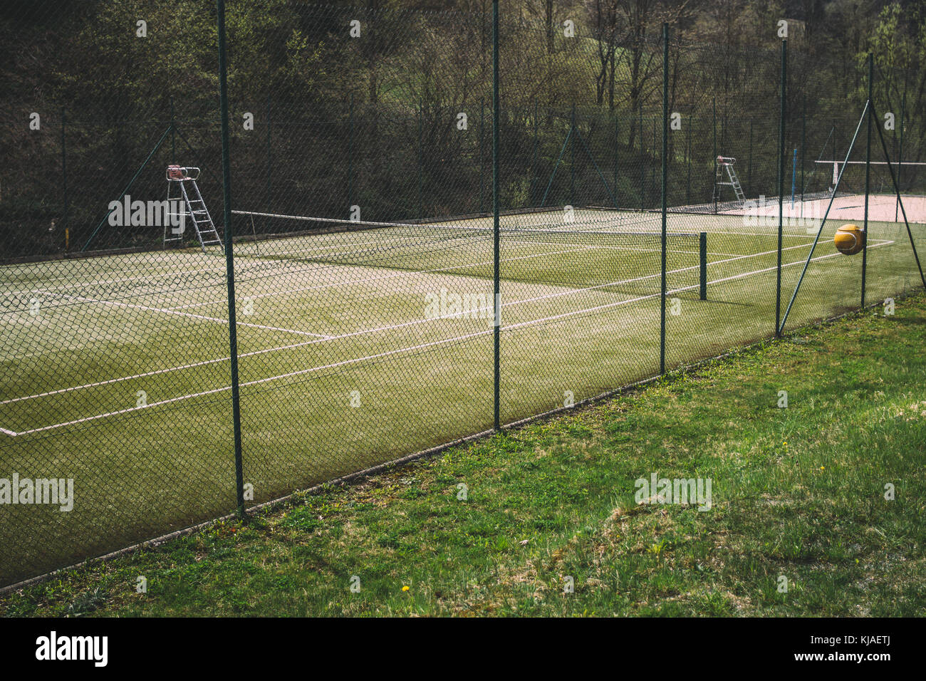 Grass tennis court behind a fence Stock Photo