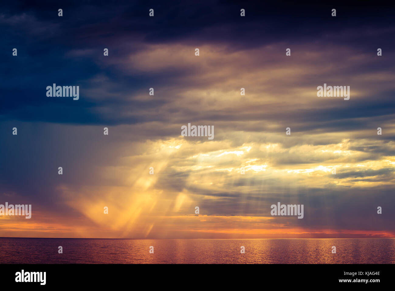 Dramatic ocean sunset with stormy clouds rain and sun rays Stock Photo ...