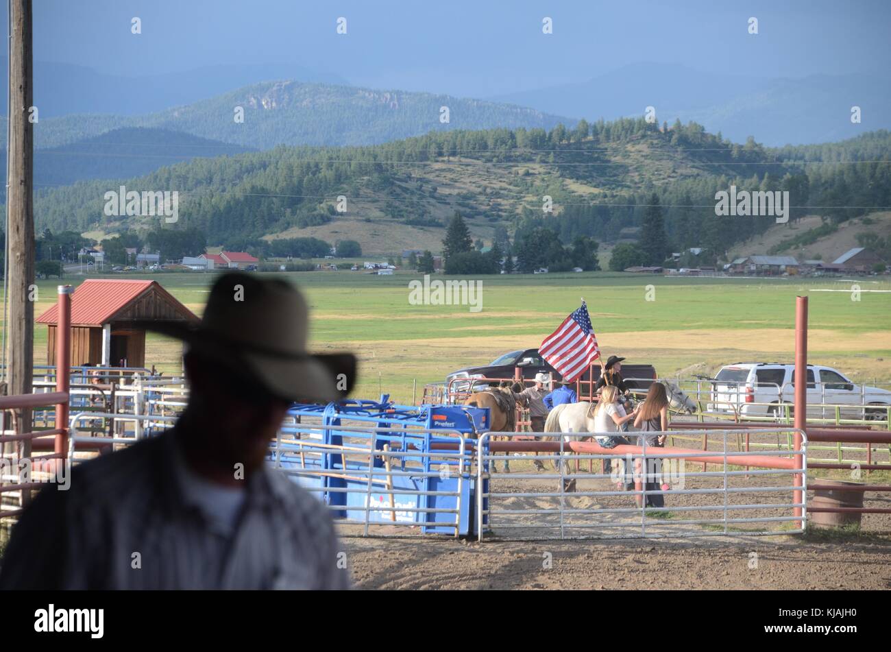 a cowboy passes in front of a cowgirl who carries the american flag at ...