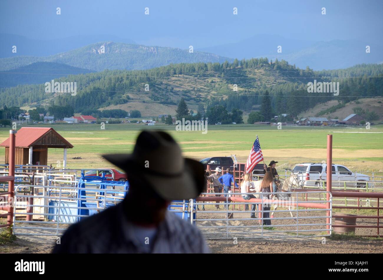 a cowboy passes in front of a cowgirl who carries the american flag at ...