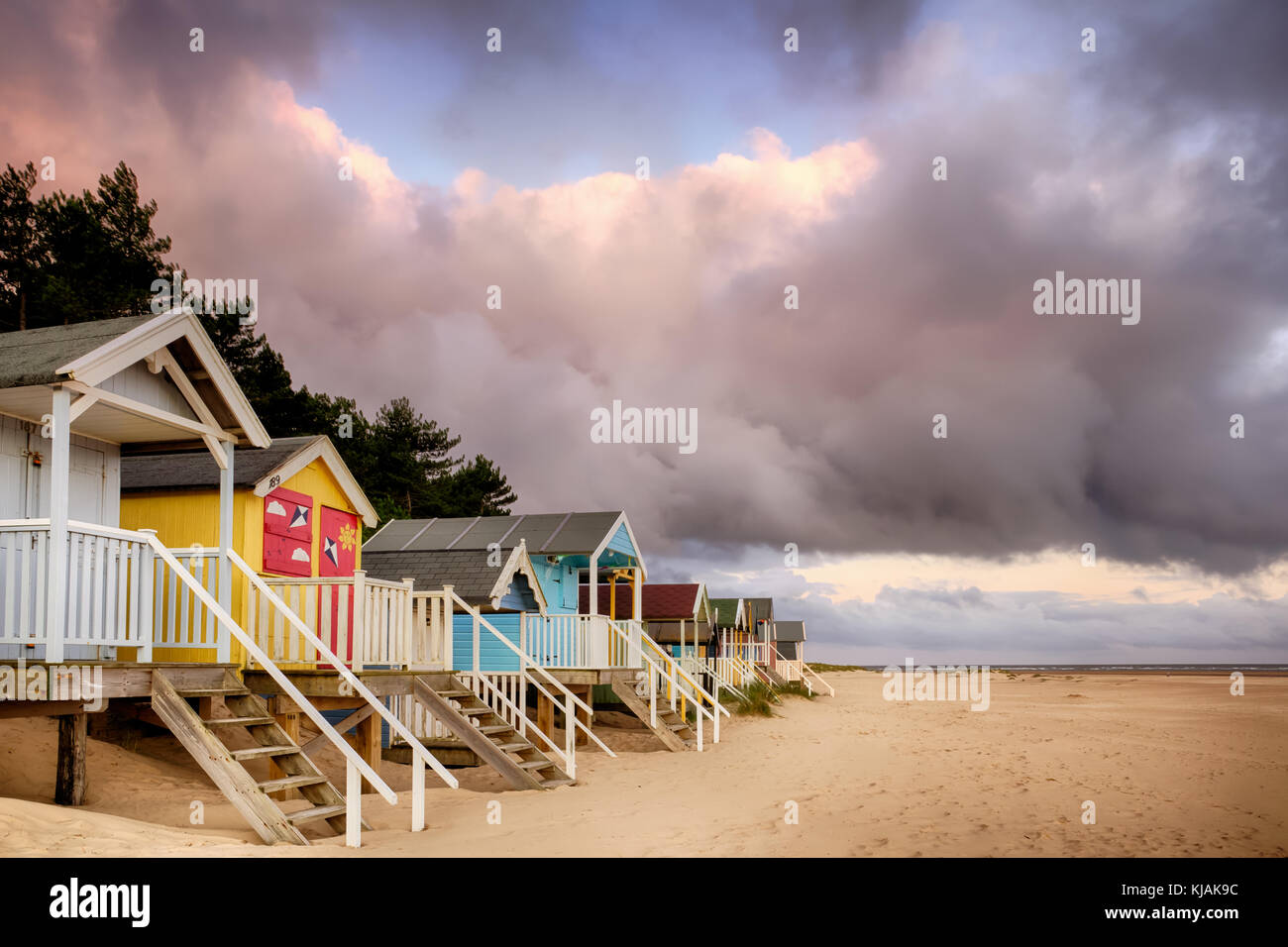 Elevated beach huts in Norfolk are some of the most colourful in England, situated on the sandy North Norfolk coast. Sunrise clouds with an early morn Stock Photo