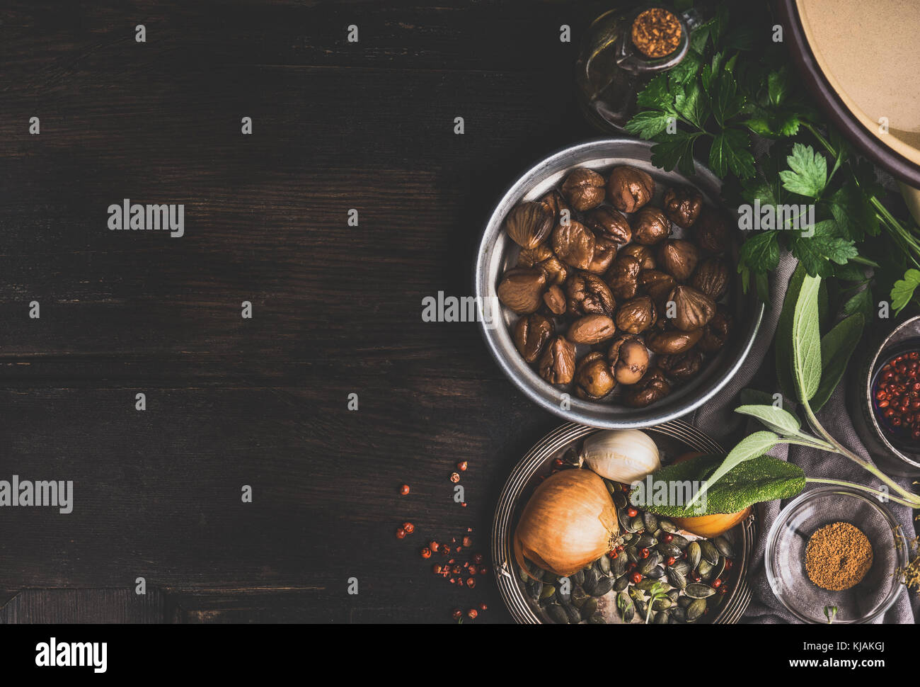 Roasted peeled chestnuts with ingredients for tasty seasonal cooking on dark rustic background, top view, place for text Stock Photo