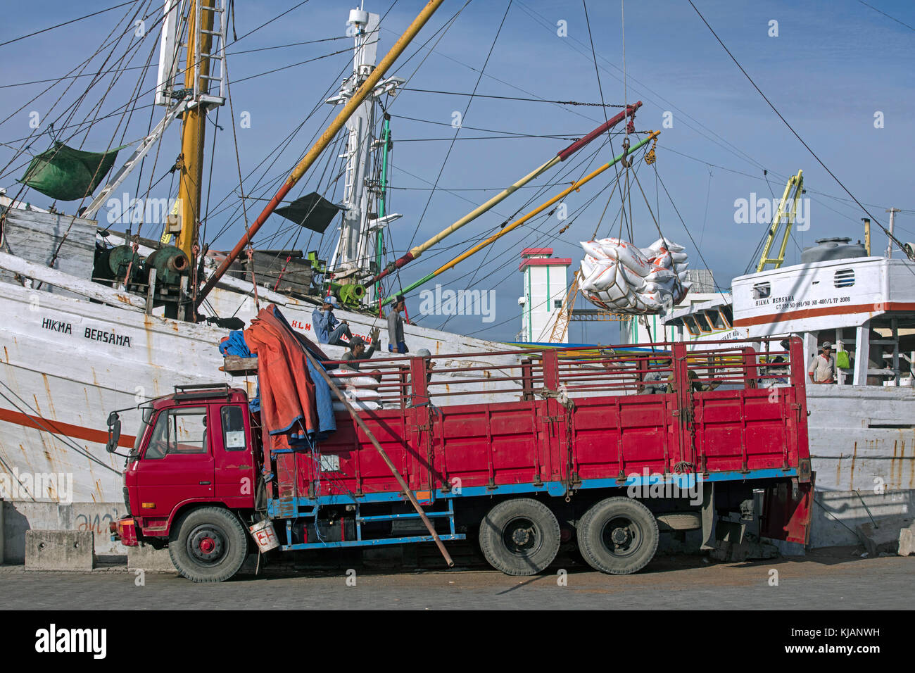 Truck loading merchandise from wooden pinisi / phinisi, traditional Indonesian cargo ship in the harbour of Semarang, Central Java, Indonesia Stock Photo