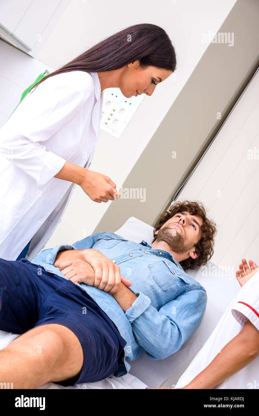 A young male patient in the emergency room getting attended by a female professional physician. Stock Photo