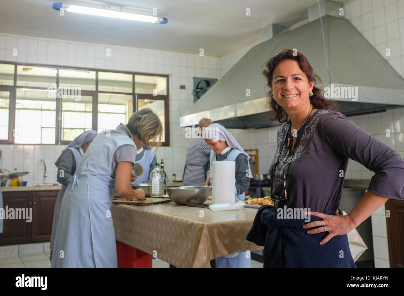 Nuns and international families preparing a party lunch in a big kitchen. Oblate nuns order Mission. Cochabamba, Bolivia. Stock Photo