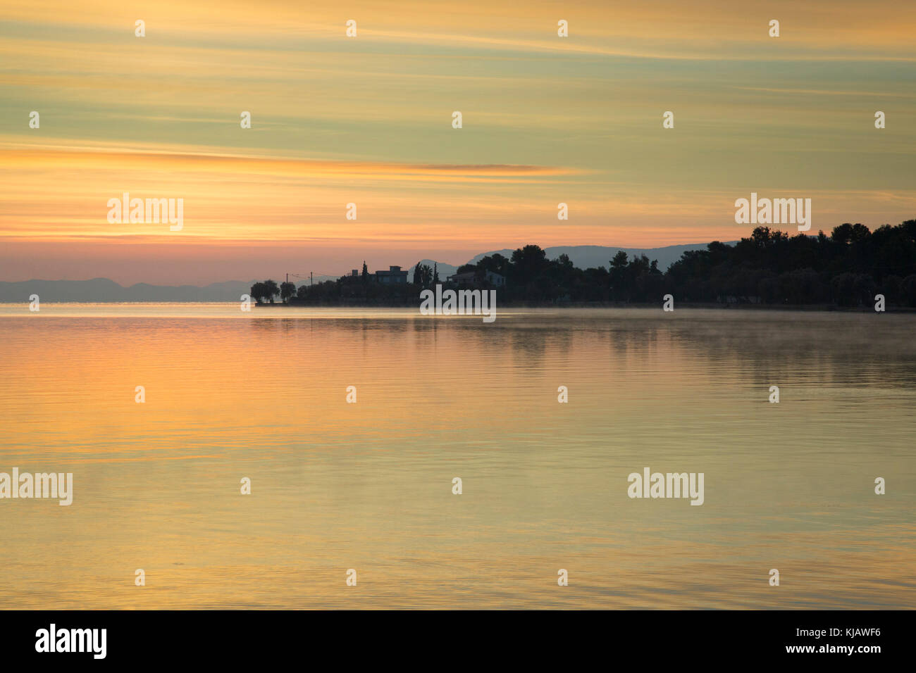 Before sunrise the colorful sky is reflected in the gentle ripples of a calm sea. Stock Photo