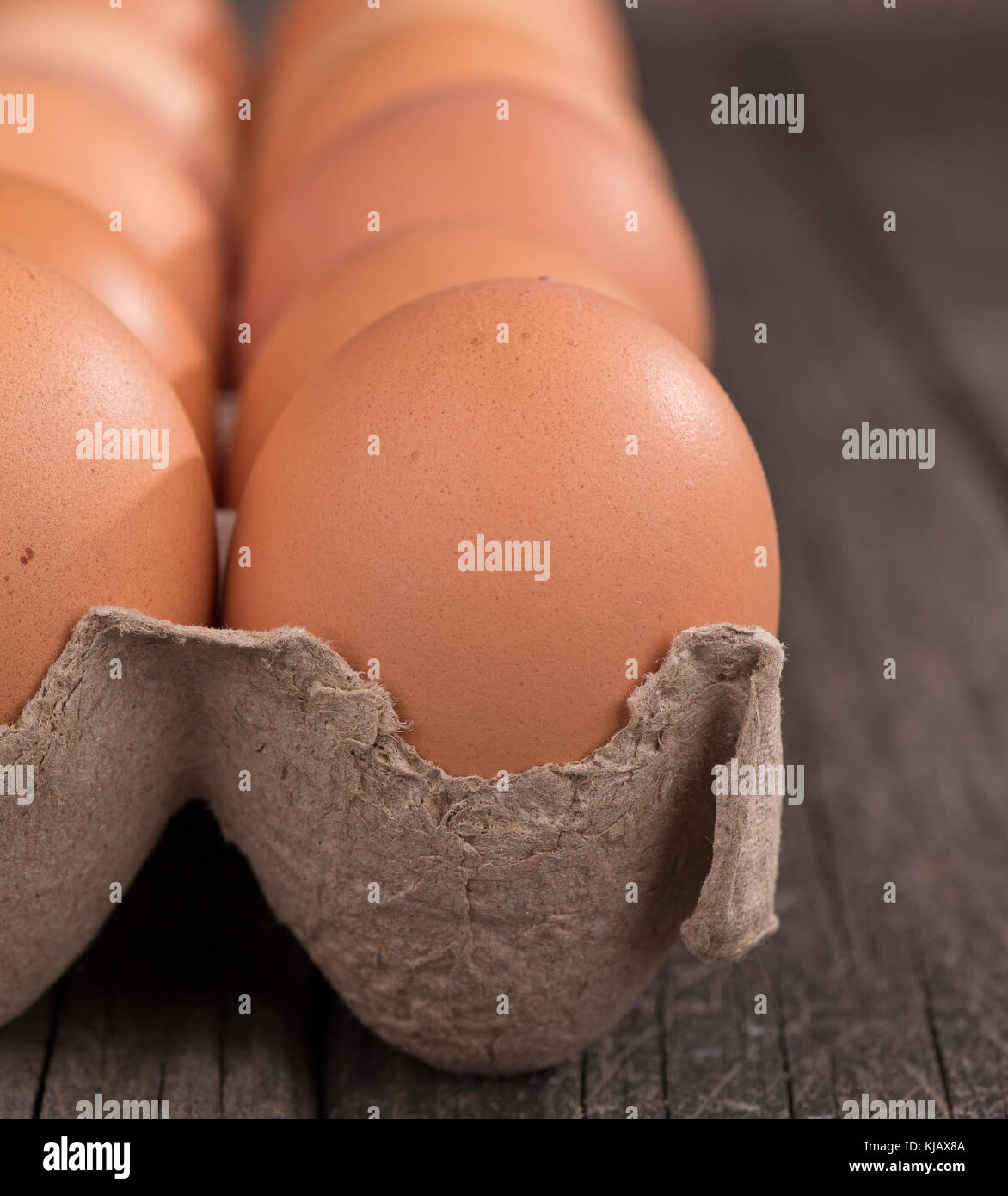 Closeup of brown eggs in a carton on a wood surface Stock Photo