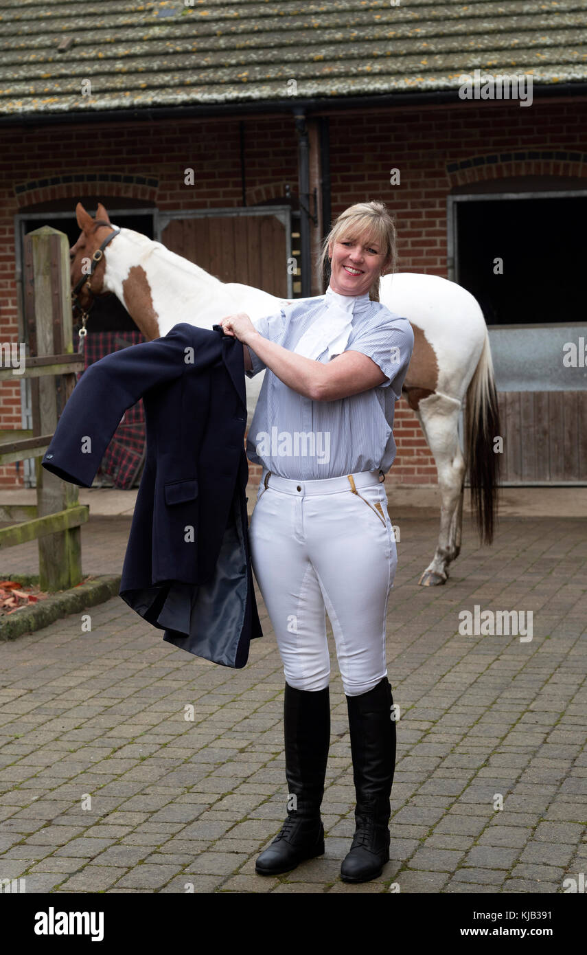 Smartly dressed horse rider putting on a dark blue riding jacket ...