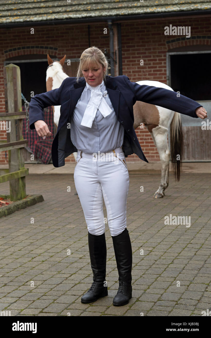 Smartly dressed horse rider putting on a dark blue riding jacket ...
