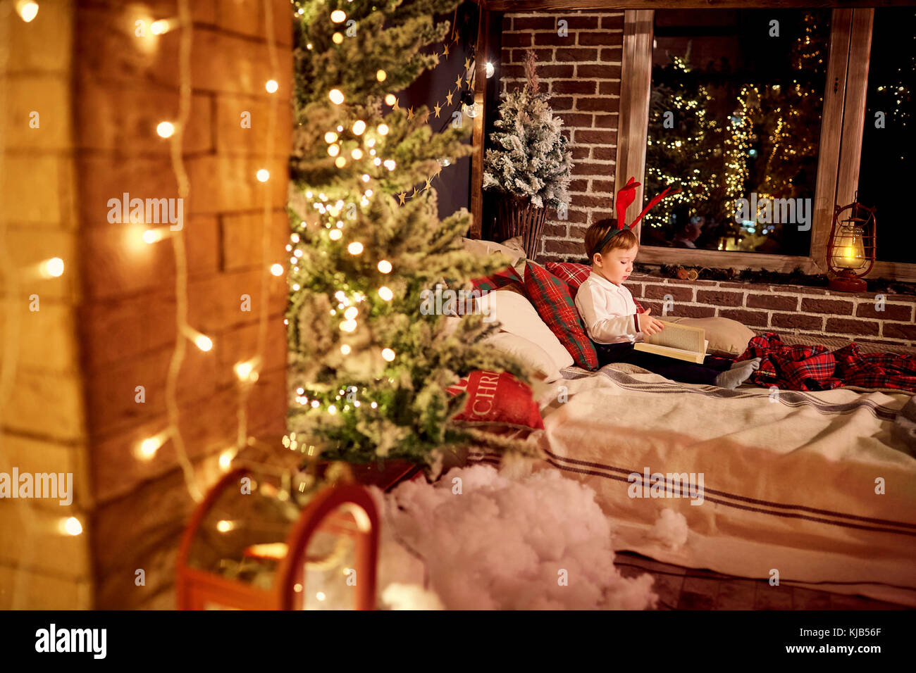 A  little boy is reading a book in the Christmas room. Stock Photo