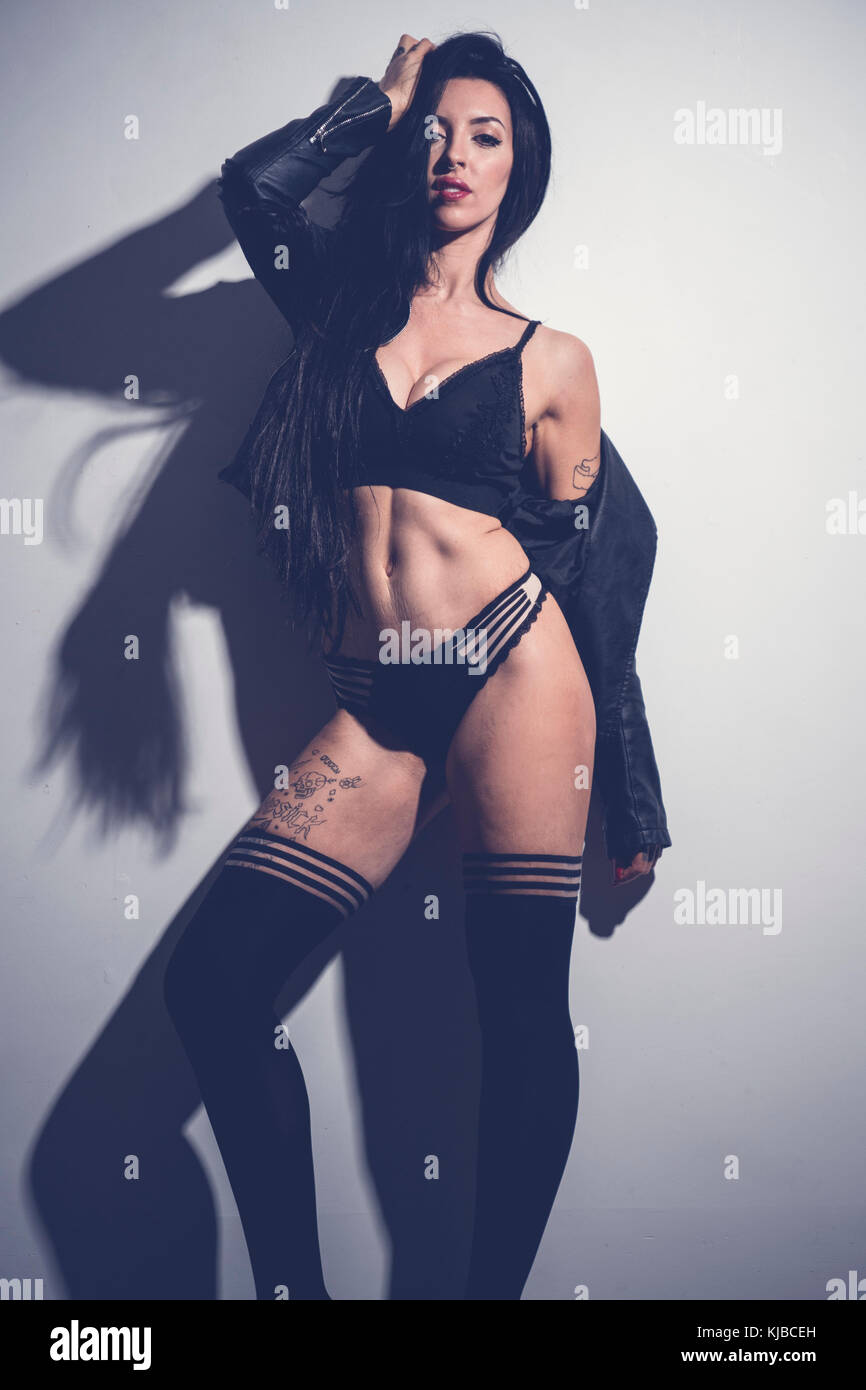 A dark haired slim caucasian heavily tattooed woman female 'alt' alternative  lifestyle model wearing stockings and lingerie posing UK Stock Photo - Alamy