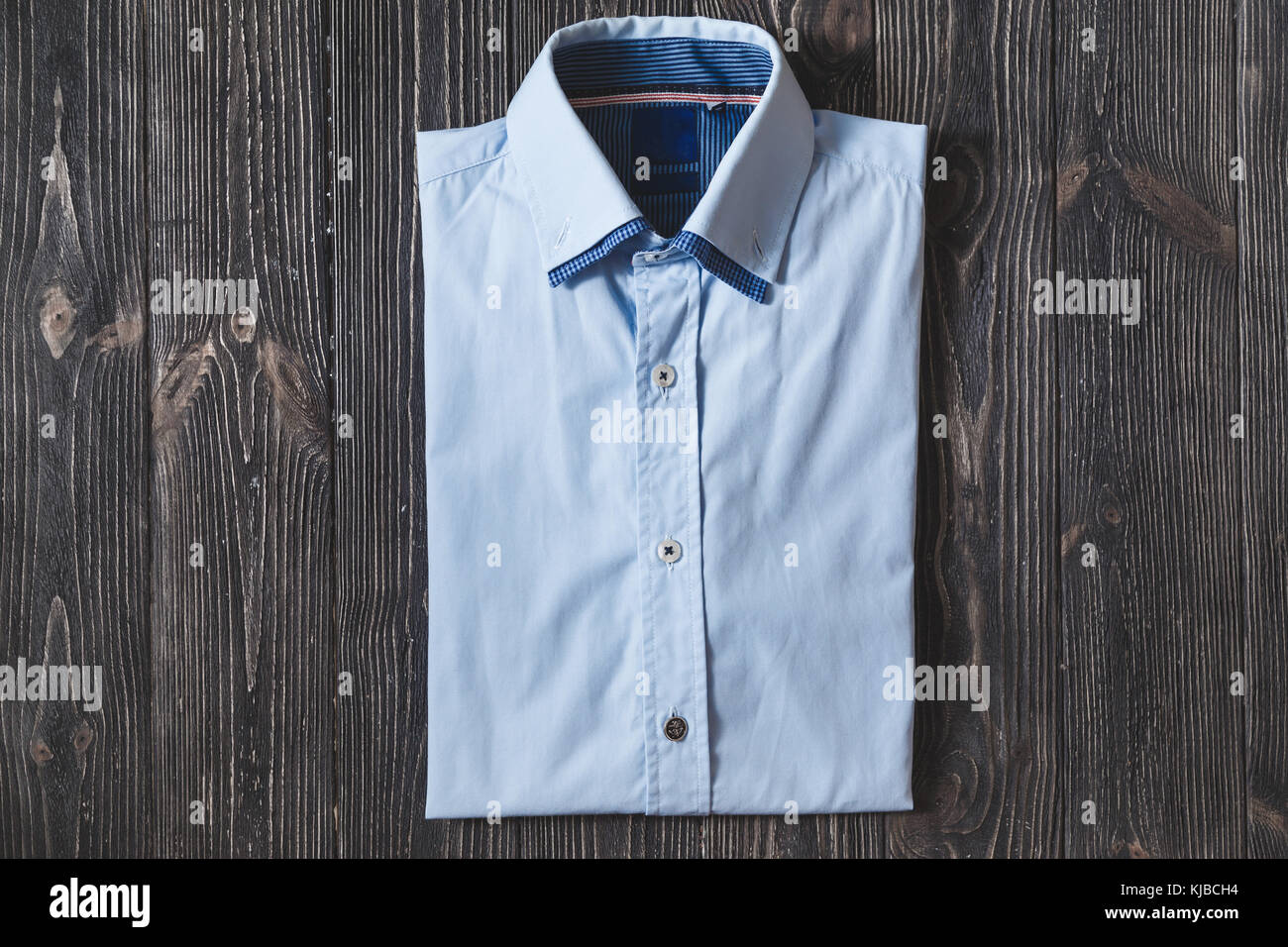 Men's classic blue folded cotton shirt with long or short sleeve on black brutal background. Stock Photo