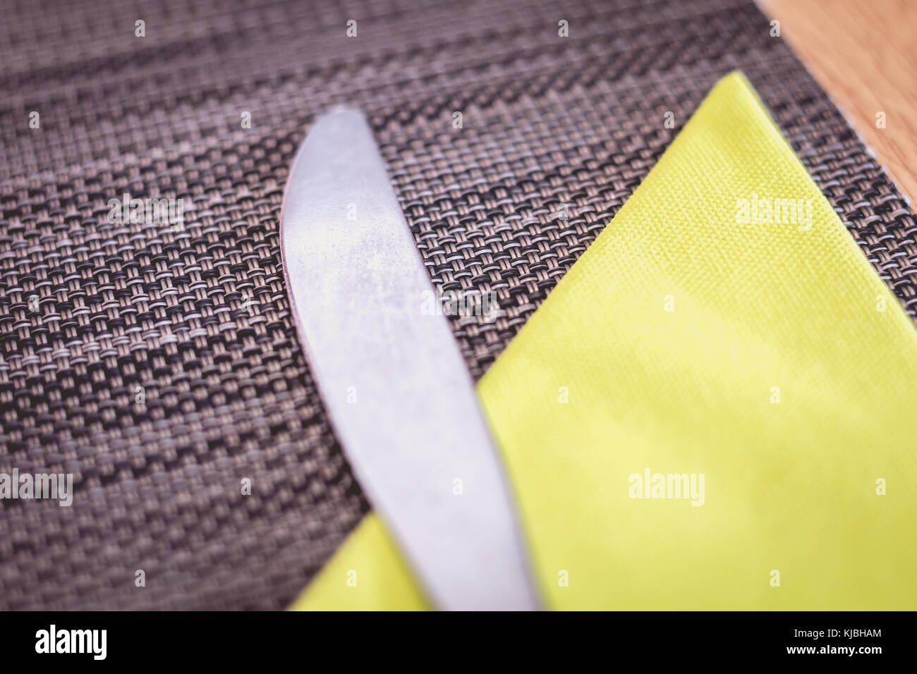 close up knife lying on a placemat with a yellow paper towel in a