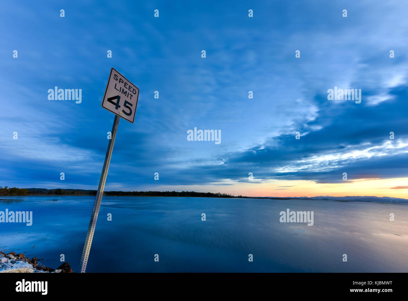 Lake Champlain between New York and Vermont at sunset. Speed limit sign as seen off of the highway, 45 MPH. Stock Photo