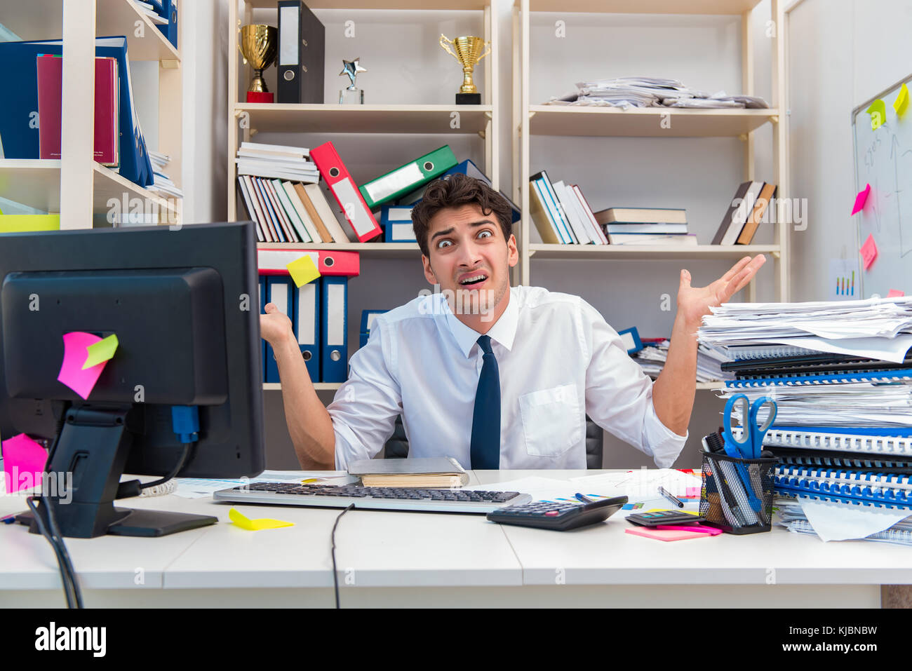 Businessman working in the office with piles of books and papers doing ...
