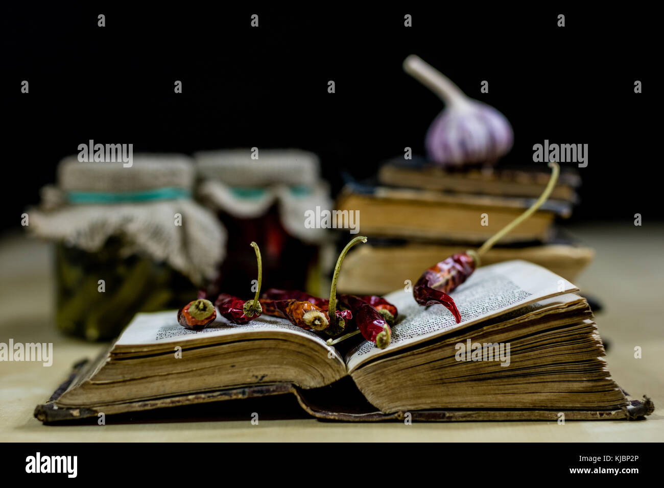 Old books and spices. Dried peppers and recipes. Old kitchen table. Black background Stock Photo