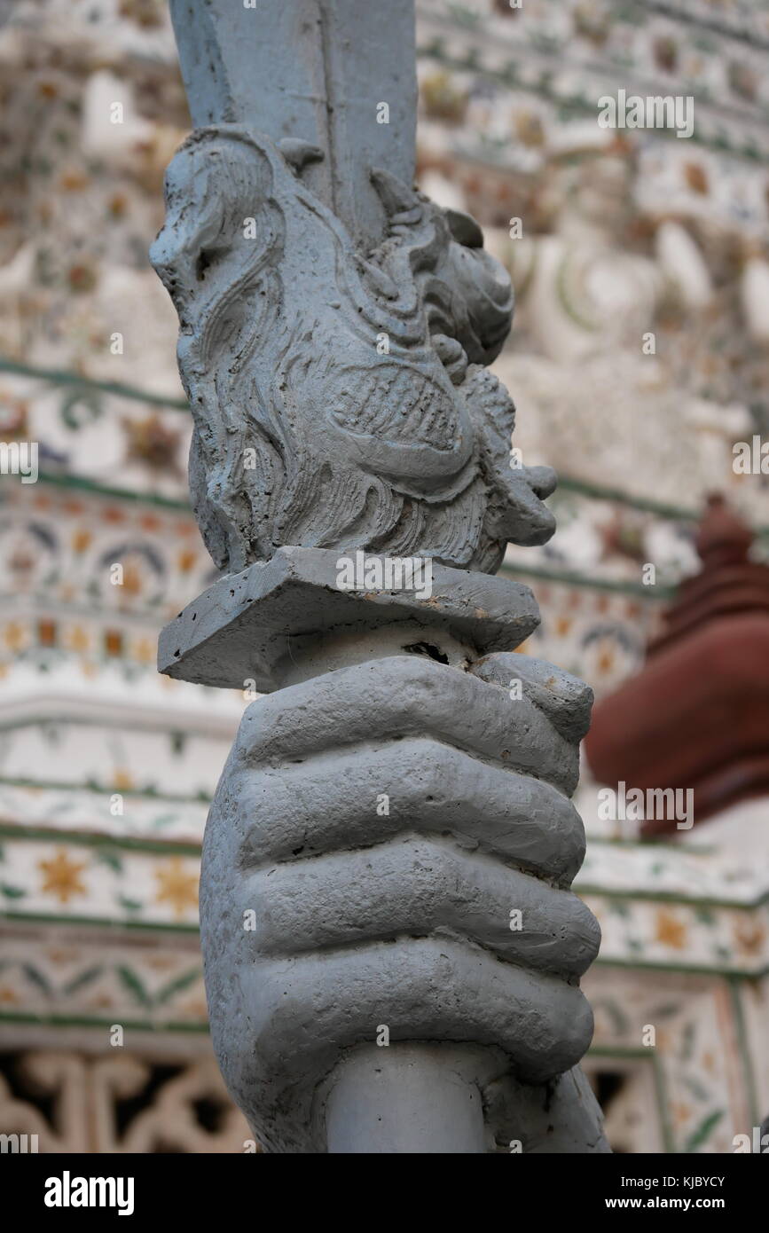 Detail of a dragon on the base of a sword's stone statue of a Chinese guardian at the entrance of Wat Arun, Bangkok, Thailand. Stock Photo