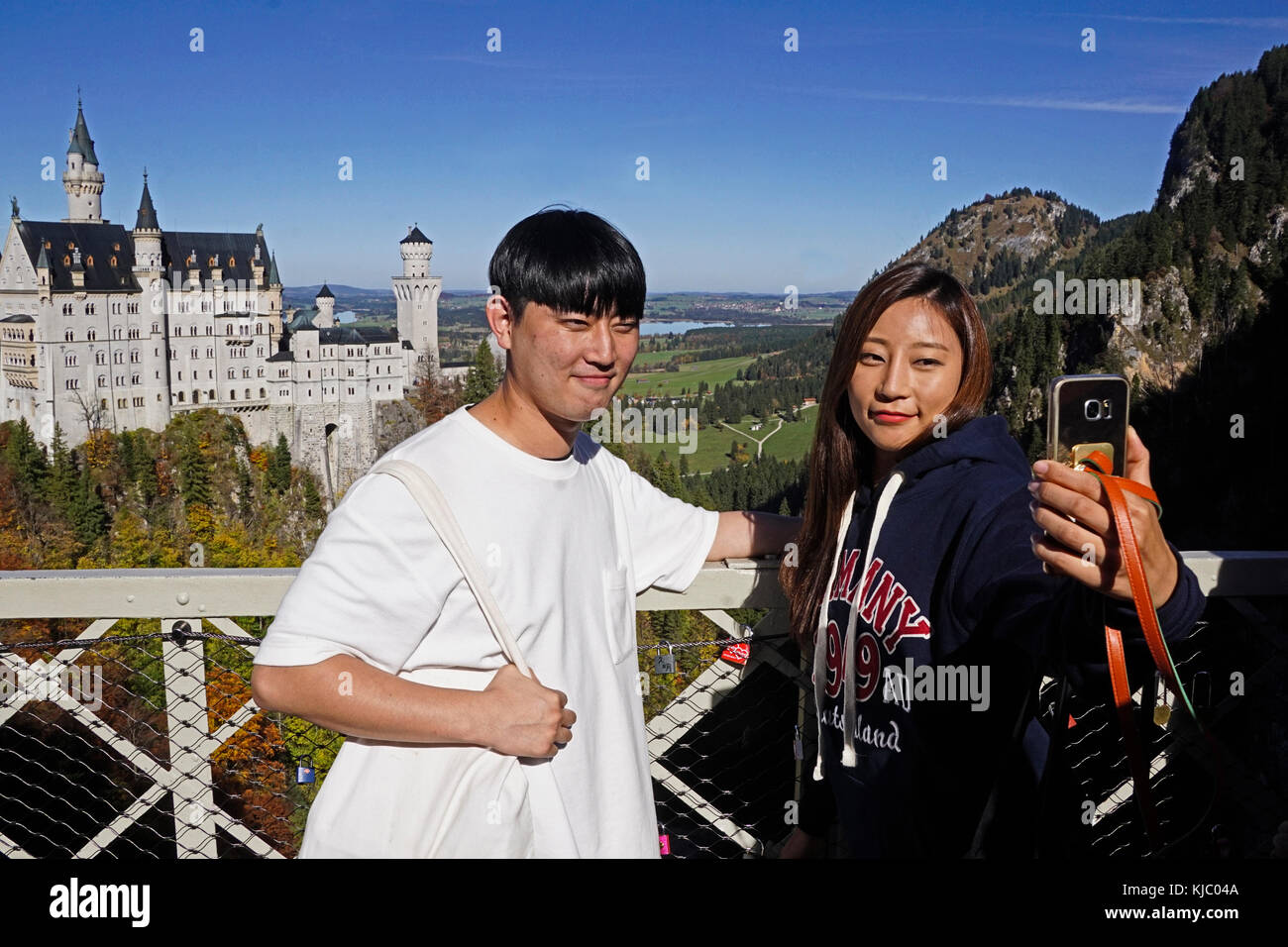 Young Chinese tourist couple doing a selfie at Neuschwanstein Castle in Bavaria, Germany. Stock Photo