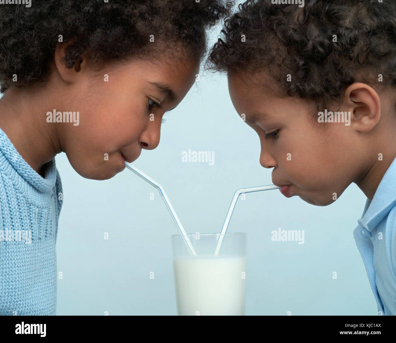 Children Sharing a Glass of Milk Stock Photo