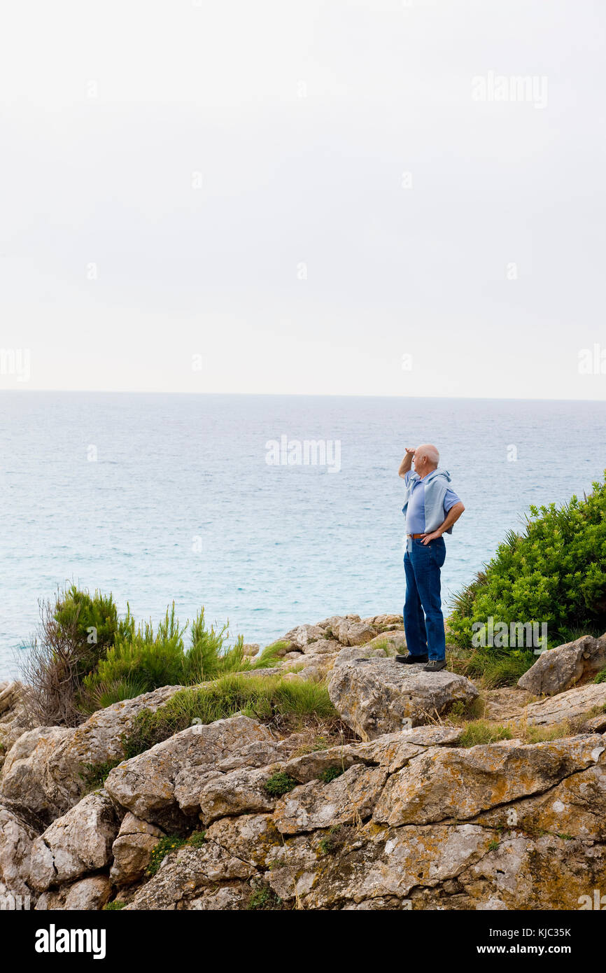 Man Standing on Cliff Looking Out at Ocean Stock Photo - Alamy