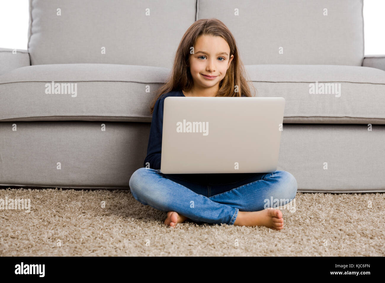Happy little girl at home working with a laptop Stock Photo - Alamy