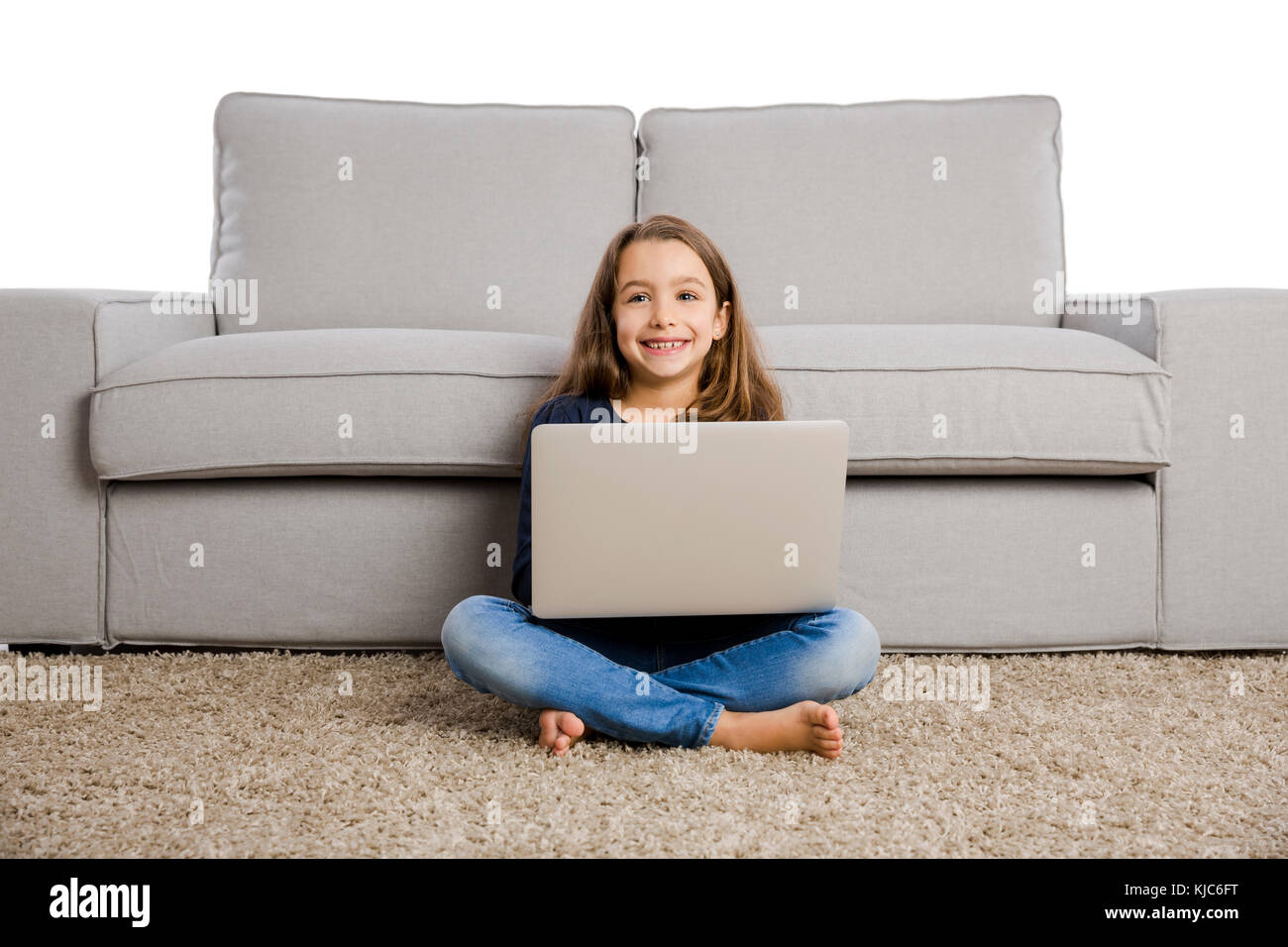 Happy little girl at home working with a laptop Stock Photo - Alamy