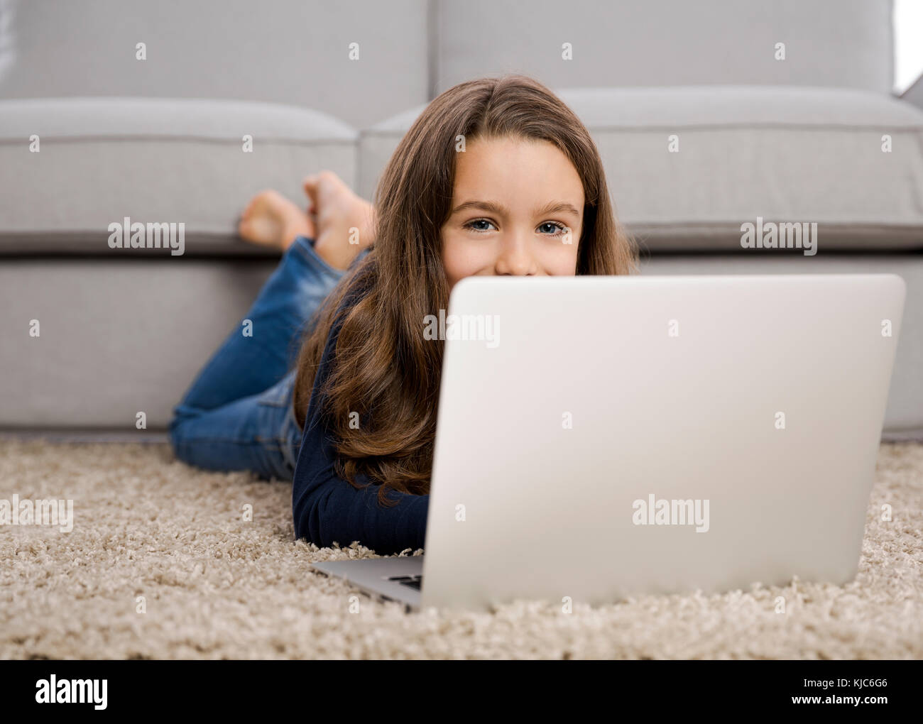 Happy little girl at home working with a laptop Stock Photo - Alamy