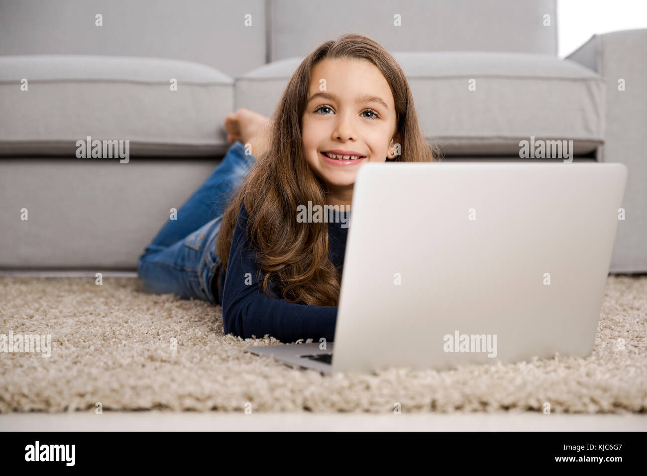 Happy little girl at home working with a laptop Stock Photo - Alamy