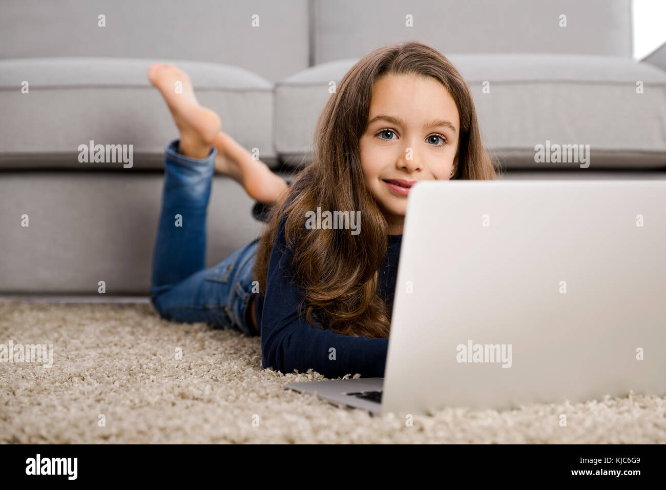 Happy little girl at home working with a laptop Stock Photo - Alamy