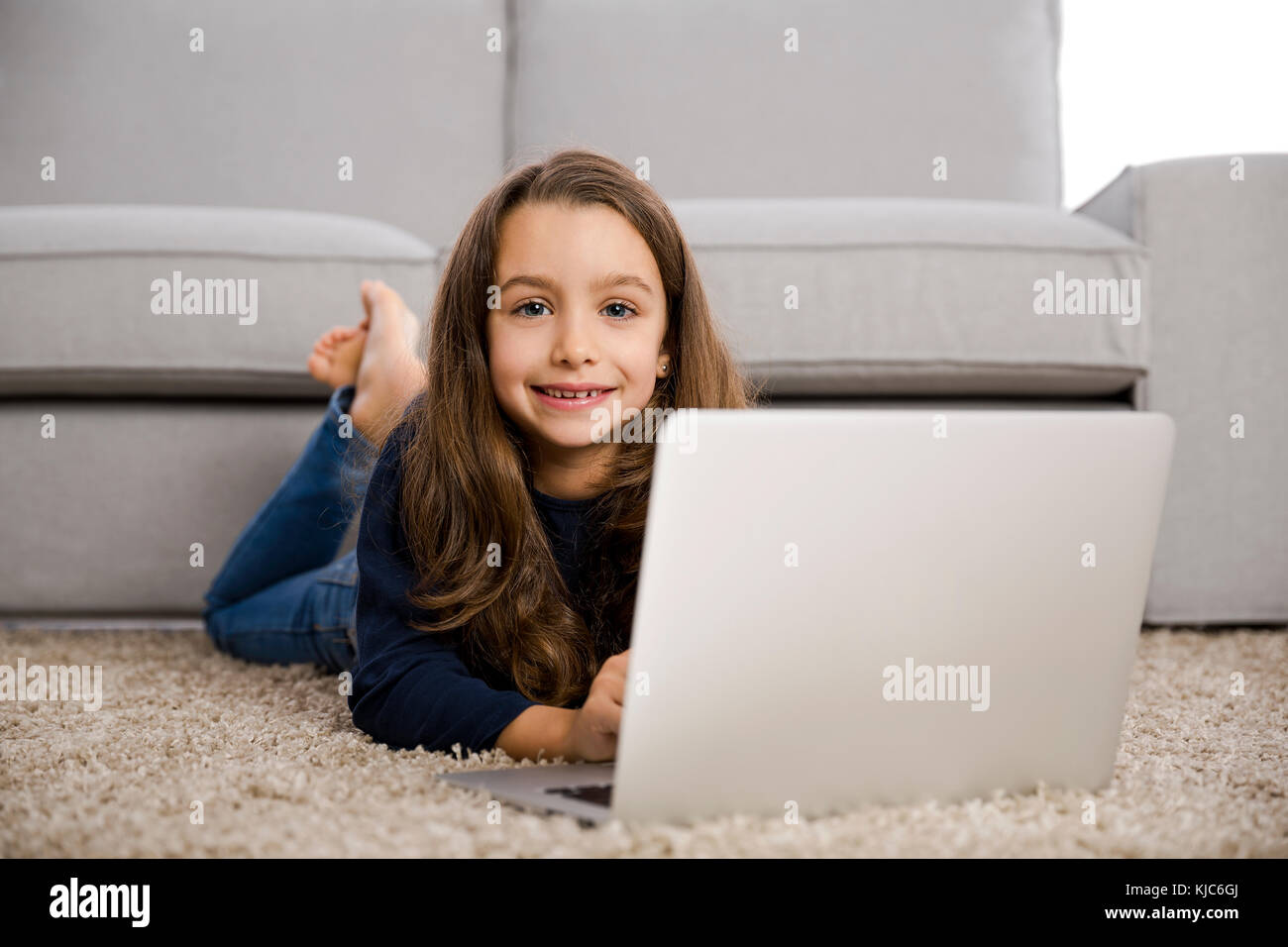 Happy little girl at home working with a laptop Stock Photo - Alamy