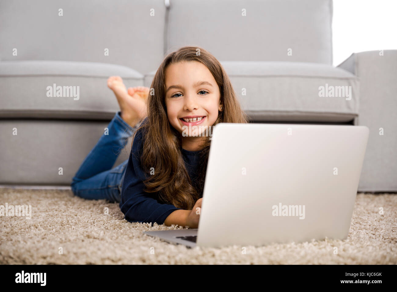 Happy little girl at home working with a laptop Stock Photo - Alamy