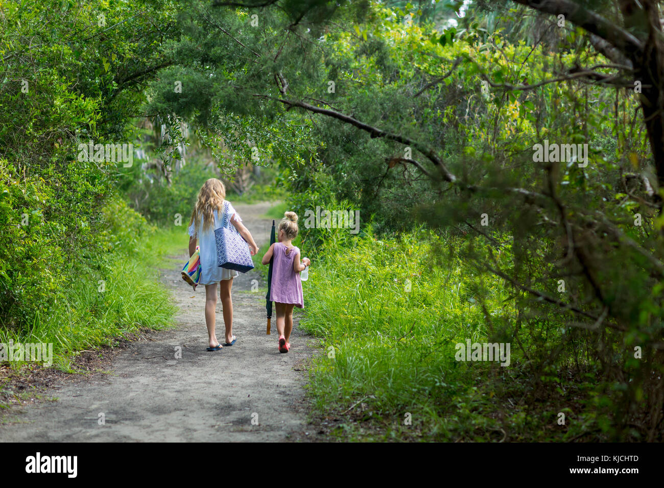 Caucasian sisters walking on dirt path Stock Photo