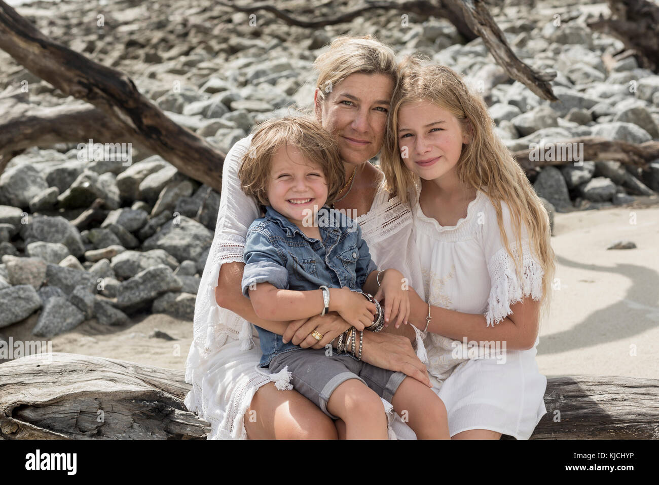 Caucasian family sitting on driftwood at beach Stock Photo