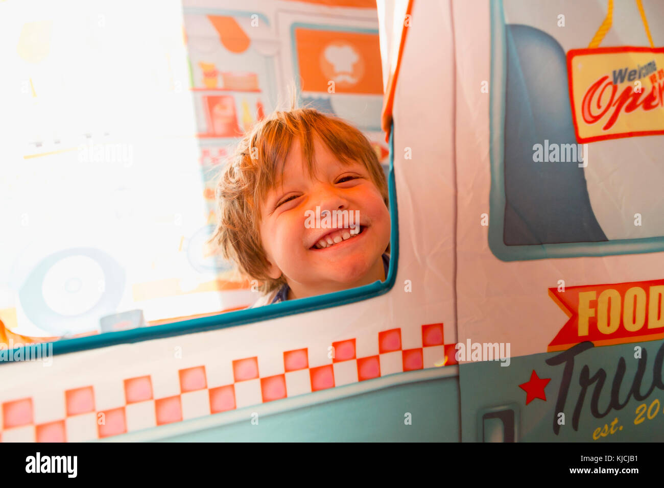 Portrait of smiling Caucasian boy in window Stock Photo