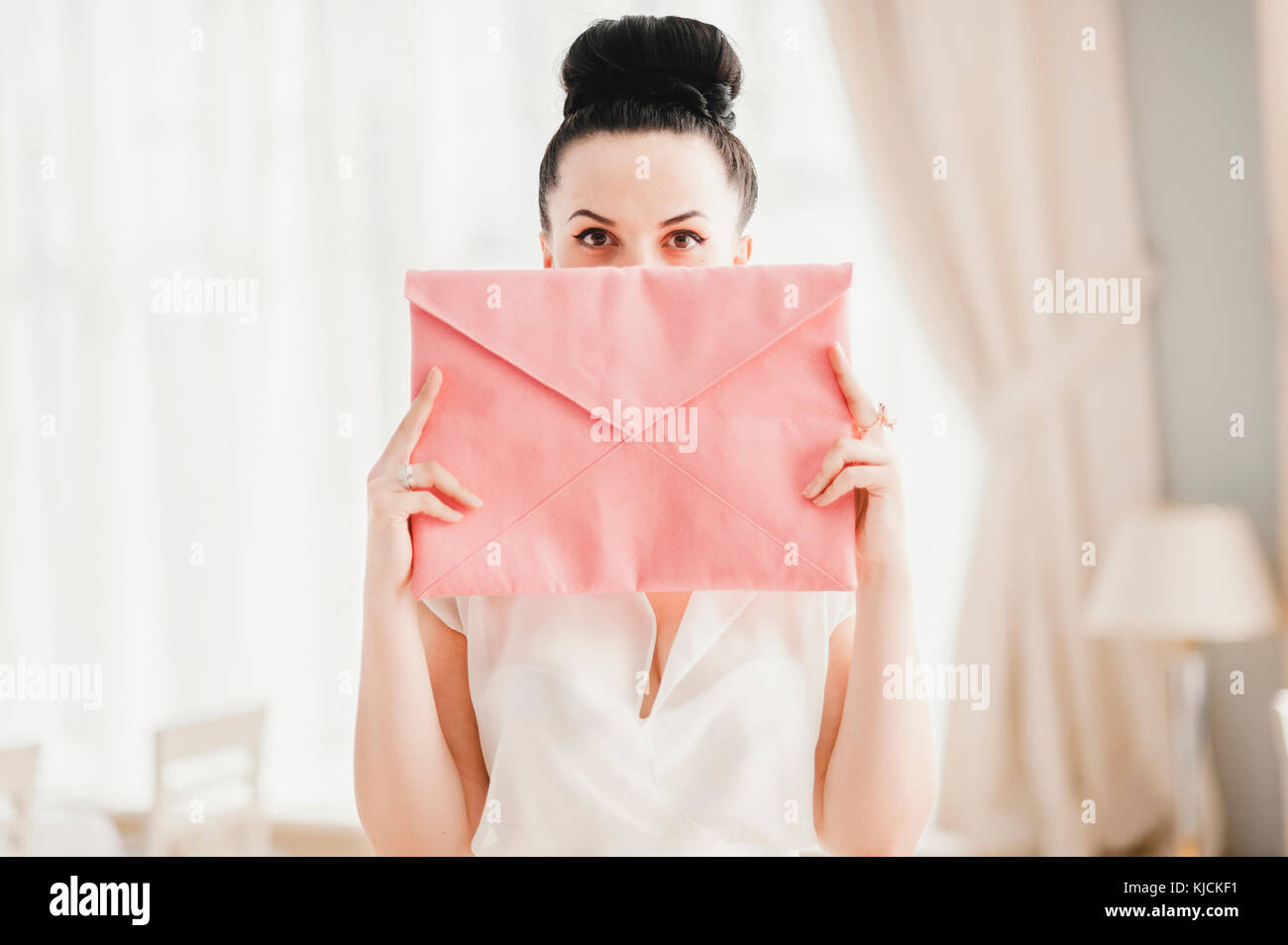 Glamorous Middle Eastern woman covering face with pink purse Stock Photo
