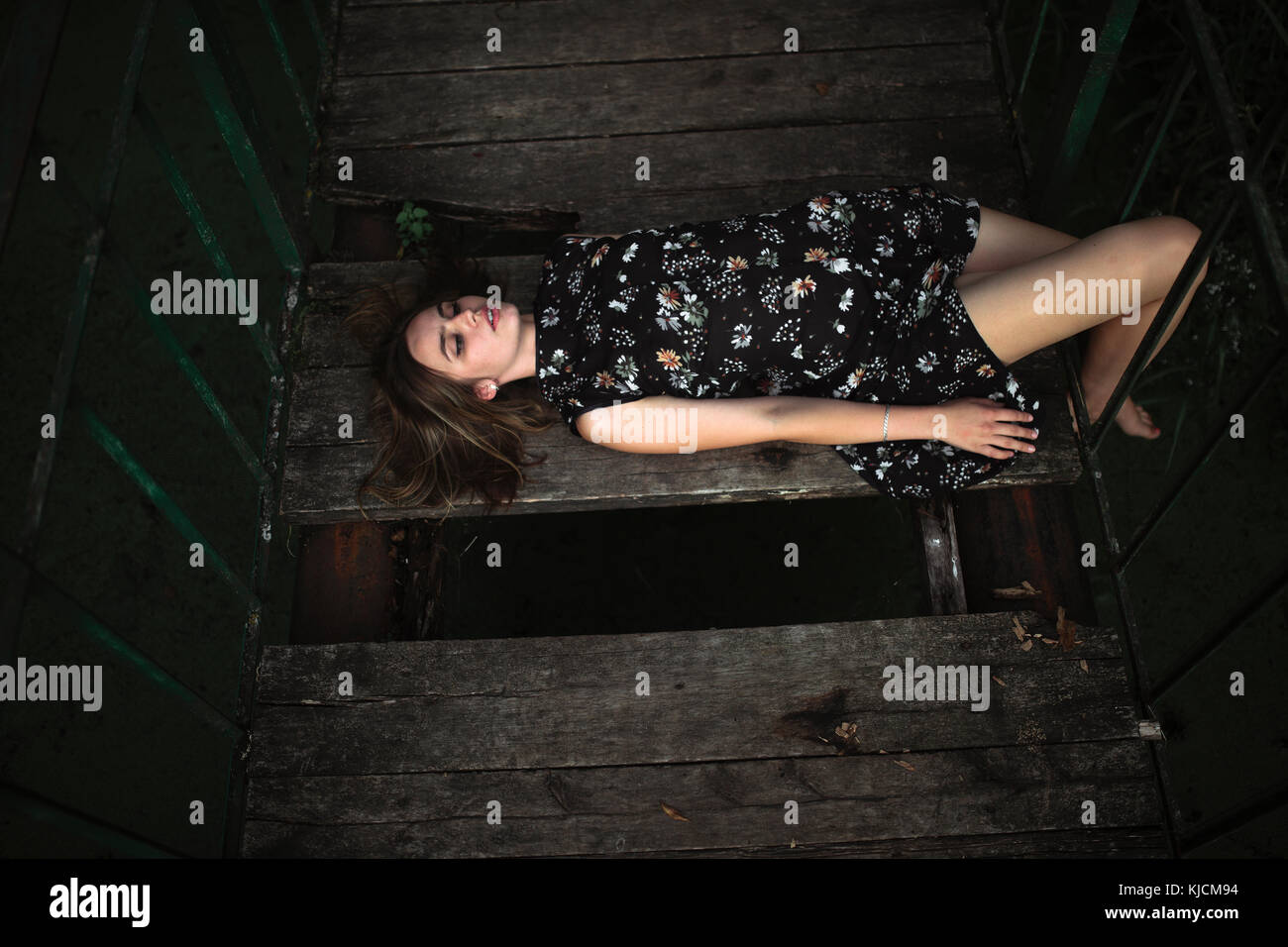 Caucasian woman laying on wooden bridge Stock Photo