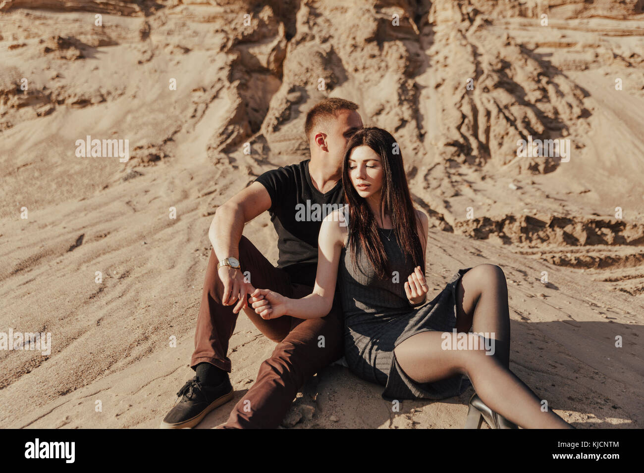 Middle Eastern couple sitting in desert Stock Photo