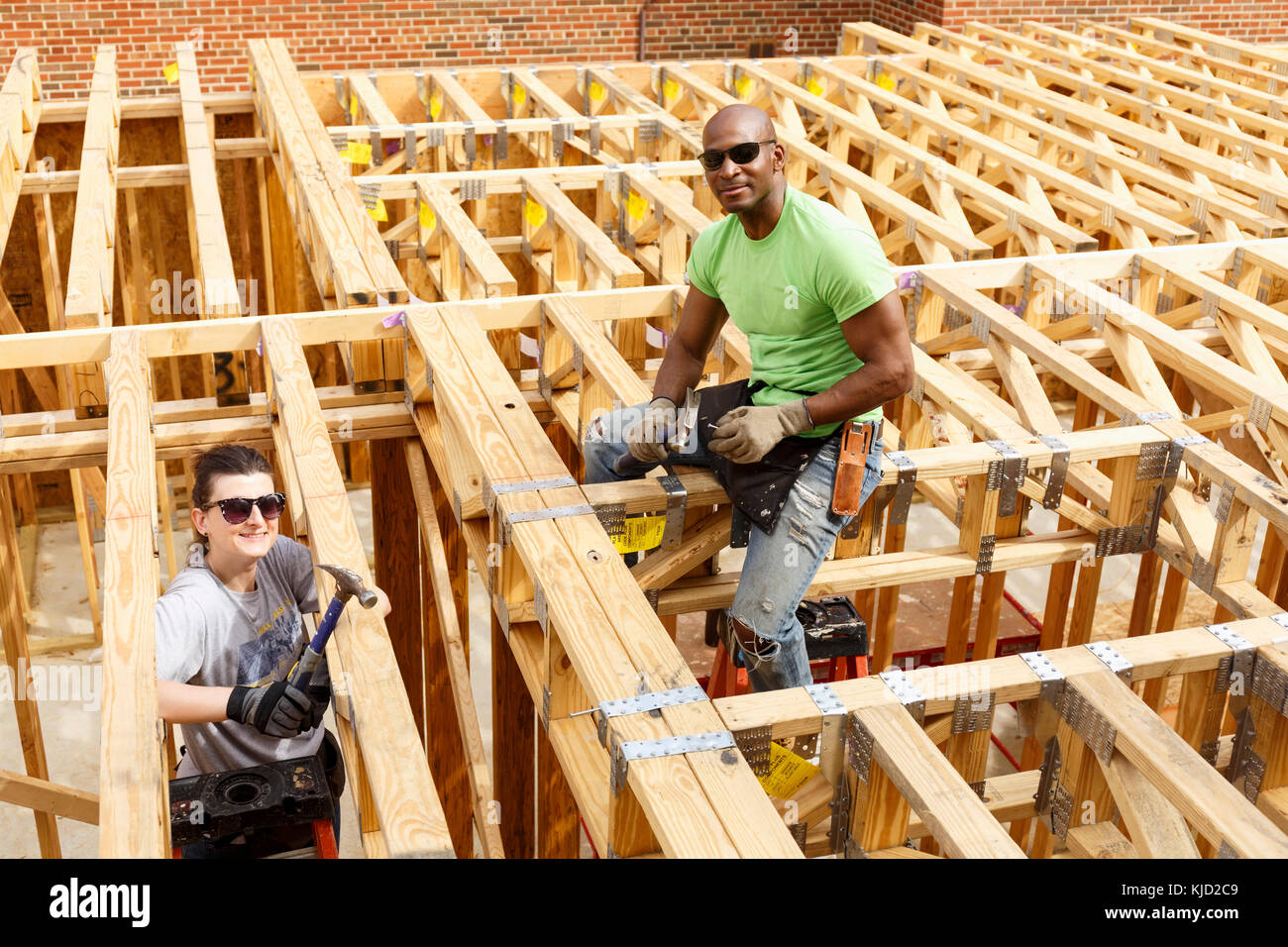 Portrait of man and woman holding hammers at construction site Stock