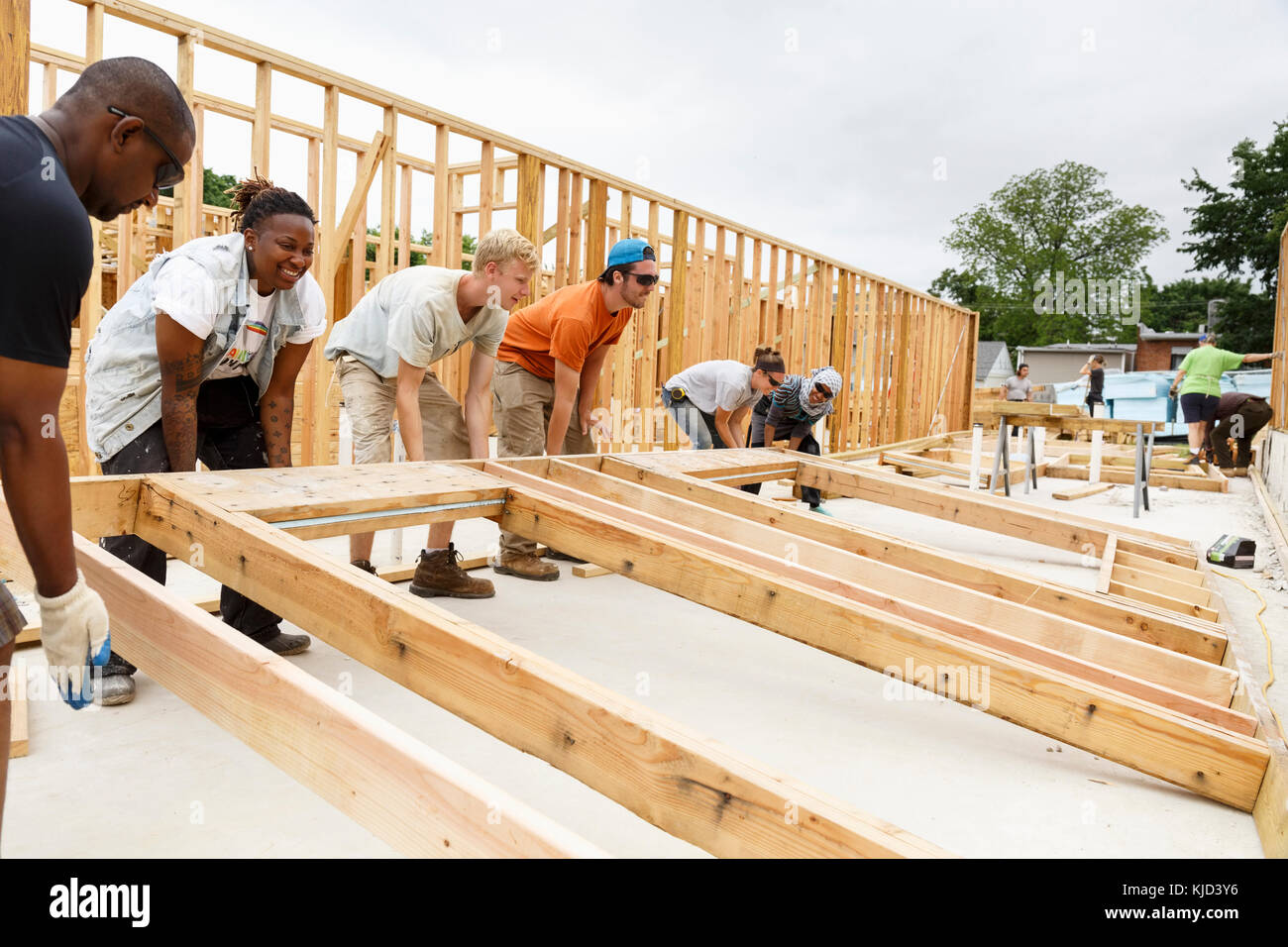 Volunteers lifting framed wall at construction site Stock Photo