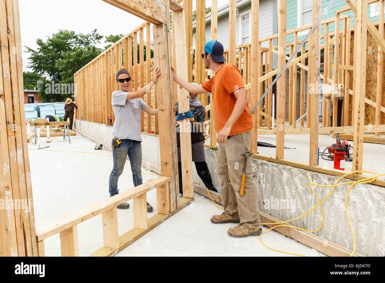 Volunteers holding framed wall at construction site Stock Photo