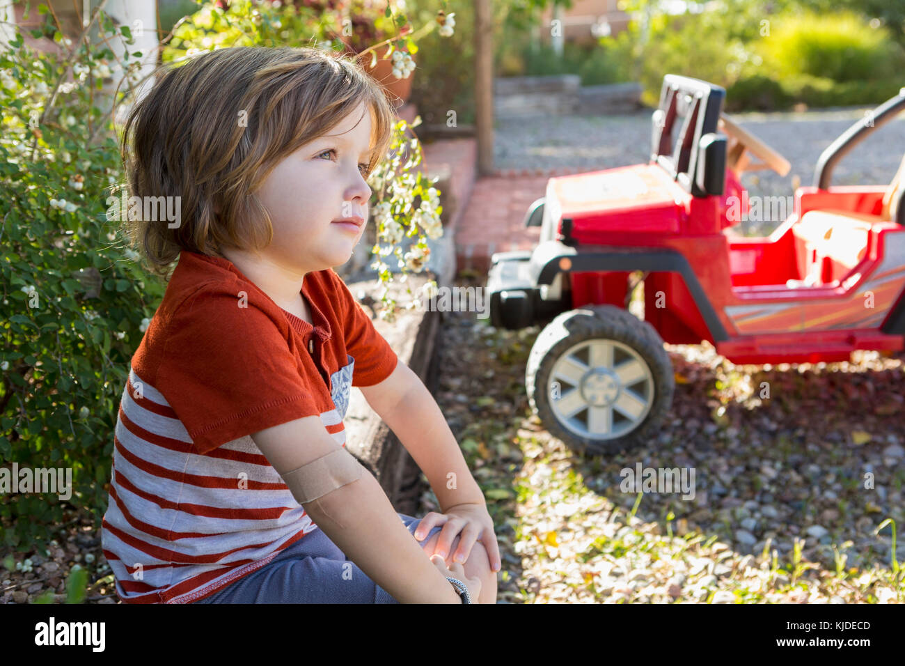Pensive Caucasian boy sitting near toy car Stock Photo