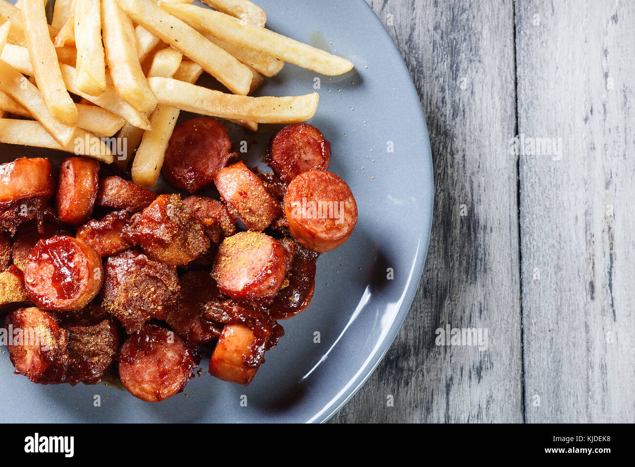 Traditional German currywurst pieces of sausage with curry sauce and french fries. Top view