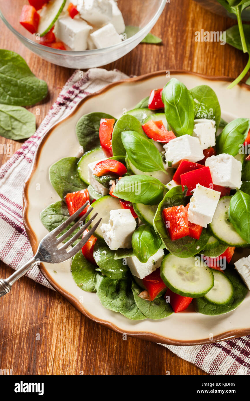 Fresh spinach salad with feta, cucumber and red paprika on a plate