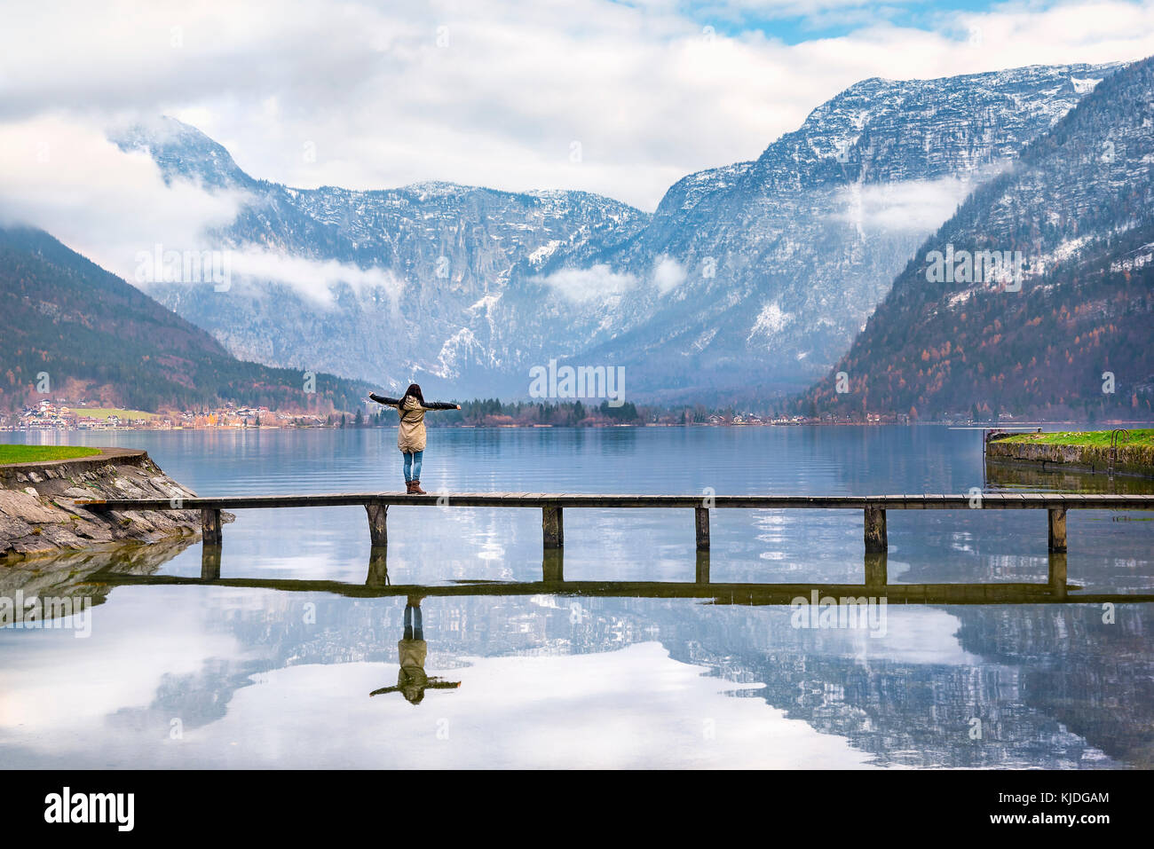 Holiday destinations theme image of a woman with open arms enjoying the lovely Hallstatter lake and the peaks of the Dachstein Mountains, in Hallstatt Stock Photo