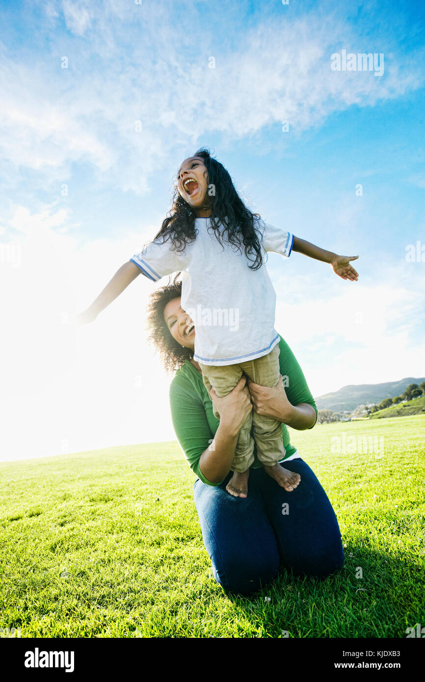 Mixed race mother holding daughter pretending to be airplane Stock Photo