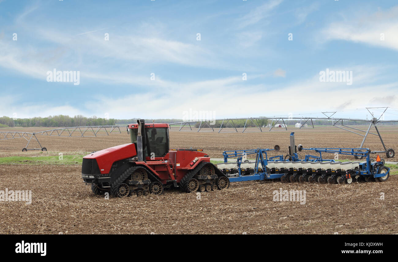 Red tractor with seeder in a farm field Stock Photo