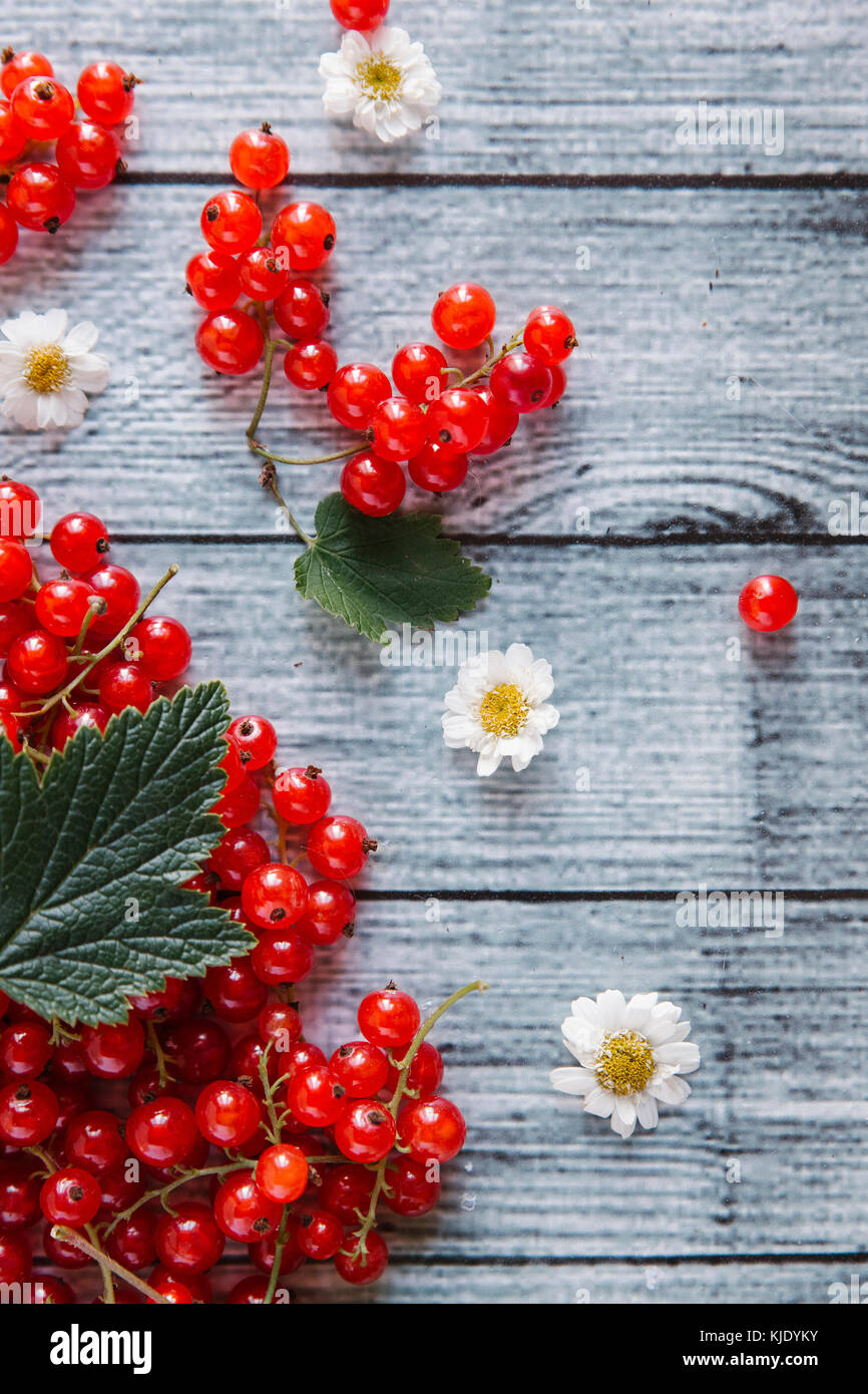Red berries and leaves on table with flowers Stock Photo