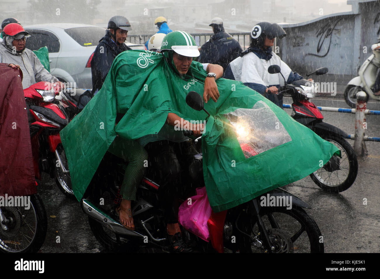 HO CHI MINH CITY, VIET NAM, Group of Asian people wear raincoat ride motorbike, difficult move in heavy rain, high wind from bad weather Stock Photo