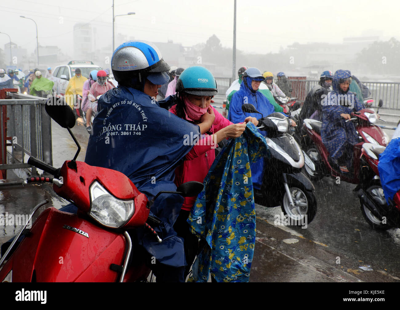 Ho Chi Minh, Vietnamese ride motorcycle, difficult move in heavy rain and high wind, couple soaking wet in bad weather by tropical low pressure Stock Photo
